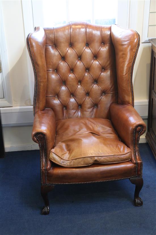 A pair of brown leather wingback armchairs,